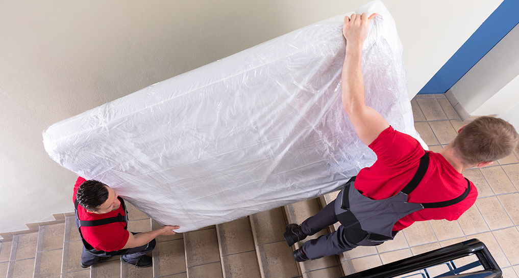 someone carrying a mattress into a building